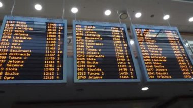 Tren istasyonunda büyük bir kalkış tahtası, tren numaralarını, kalkış saatlerini, rayların numaralarını ve varış noktalarını listeler..