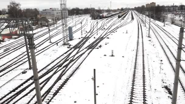 鉄道トラックの広大な景色は 冬を示す雪で覆われて コンバージョンと分岐しています 複数の平行線は 主要な鉄道ジャンクションまたは列車ヤードを示唆しています — ストック動画