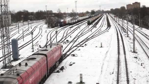 雪は鉄道の庭を覆い トラックが交差し 貨物列車がその道を通り抜ける ベアツリーと産業構造は 冬の季節の輸送と物流への影響を強調するシーンをフレーム — ストック動画