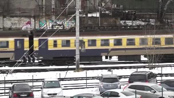 拉脱维亚里加 2023年12月27日 冬季的白天场景 一列黄色和蓝色的客运列车穿过一个被雪覆盖的铁路车站 — 图库视频影像