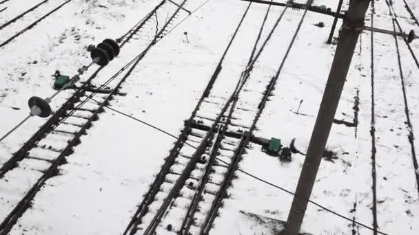 冬の間の鉄道トラックの空中視界 地面を覆う雪 列車のスイッチングエリアを示す複数のトラックが交差し ダイバージします — ストック動画