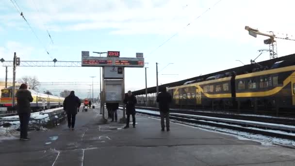 黄色和黑色的火车停在雪地覆盖的铁路站台上 头上的电线伸展在上面 表示电气化的铁路系统 — 图库视频影像