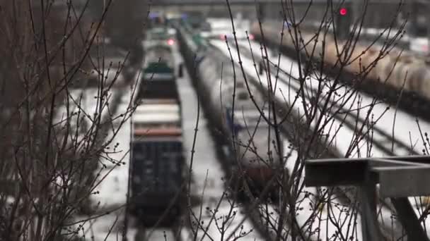 冬の鉄道ヤードを移動する列車は 寒い季節に鉛機関車 信号および通過のアプローチに焦点を当てて裸の木の枝を通って見られます — ストック動画
