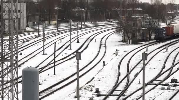 一个庞大的铁路网在寒冷的天空下展开 铁轨在白雪覆盖的景观中穿行 工业的氛围是可以感觉到的 空荡荡的车厢在等待着他们的下一次旅程 遥远的建筑矗立在寂静寒冷的景象之上 — 图库视频影像