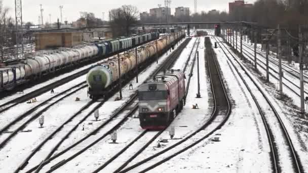 雪は鉄道の庭を覆い トラックが交差し 貨物列車がその道を通り抜ける ベアツリーと産業構造は 冬の季節の輸送と物流への影響を強調するシーンをフレーム — ストック動画