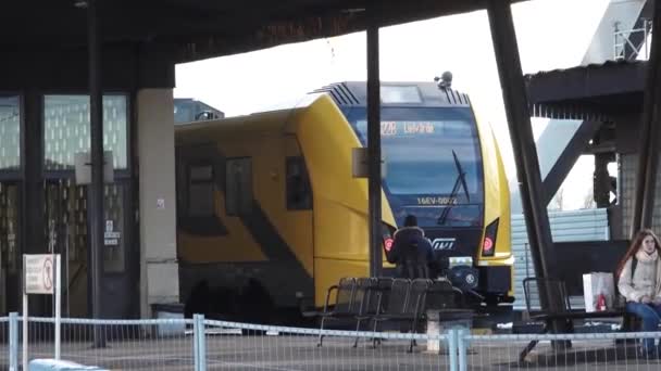 一个背负背包的人走近车站月台上的一辆黄色火车 车上坐着等候的乘客 — 图库视频影像