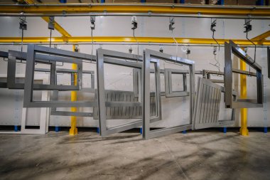 Endüstriyel bir ortam. Üzerinde birkaç büyük gri ahşap pencere çerçevesi ya da bina var..