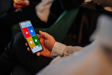 Riga, Letonya - 6 Aralık 2023 - Kahoot uygulaması açık olan akıllı telefonu tutan ve bir yarışma oyunu için renkli cevap düğmeleri gösteren bir elin yakın çekimi.