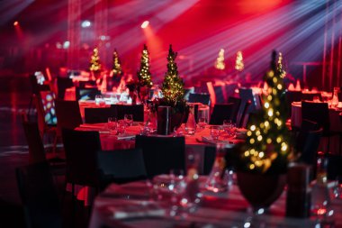 Şenlik şöleni masaları cam süslemeli ve Noel ağaçlarını dinamik kırmızı ve beyaz ışıklandırmalar altında süslemeli..