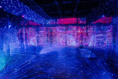 Tavan lambaları yansıyan yer aynalı duvarlar ve zemin, yıldızlı, mavi ve pembe bir görsel efekt yaratır..