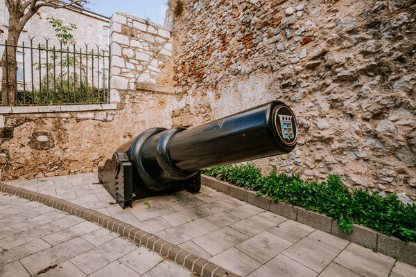 Gibraltar, Britain - January 24, 2024 -  old black cannon on display in front of a stone wall with green shrubbery.