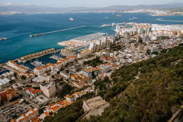Gibraltar, Britain - January 24, 2024 - Gibraltar with a marina, dense urban area, and a view of the sea with ships, extending to distant mountains.