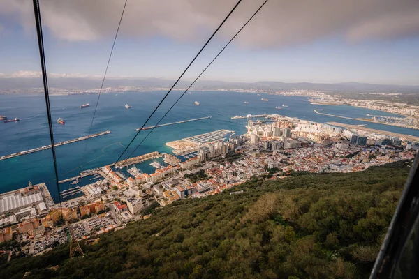 Gibraltar, Britain - January 24, 2024 - Gibraltar from a cable car, with a panoramic view of the city, marina, and the Strait with ships.