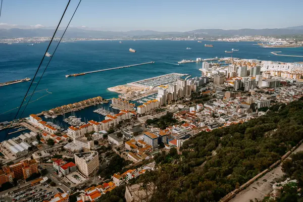 Gibraltar, Britain - January 24, 2024 - Gibraltar with a marina, dense urban area, and a view of the sea with ships, extending to distant mountains.