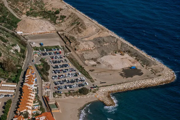 Gibraltar, Britain - January 24, 2024 - Aerial view of a parking lot by the sea, next to a beach and a construction site.