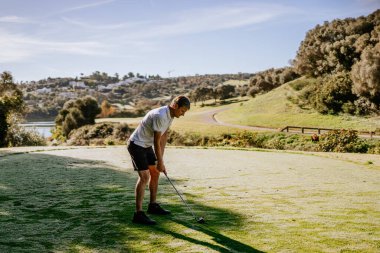 Sotogrante, İspanya - 25 Ocak 2024 - Golf sahasında golf topu havada sallanan golfçü, ağaçlar ve patika manzaralı arka plan.