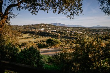 Sotogrante, İspanya - 25 Ocak 2024 - Açık bir gökyüzü altında bir golf sahası, tepeler, ağaçlar ve binaların manzarası.