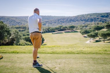 Sotogrante, İspanya - 25 Ocak 2024 - Bir golfçü arka planda bir golf sahası ve ağaçlarla atış yaptıktan sonra çadırı gözlemler.