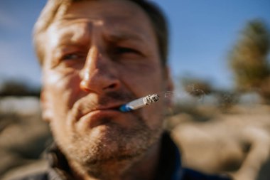 Sotogrante, İspanya - 25 Ocak 2024 - Yakın plan çekimde yanan uçla sigara içen bir adam, bulanık arka plan.