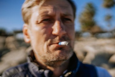 Sotogrante, İspanya - 25 Ocak 2024 - Yakın plan çekimde yanan uçla sigara içen bir adam, bulanık arka plan.