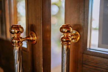 Sotogrante, İspanya - 25 Ocak 2024 - arka planda yansıma ve bokeh olan ahşap kapıların altın kapı kolları.