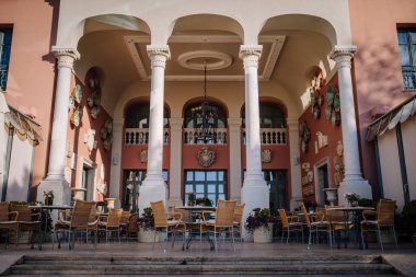 Sotogrante, İspanya - 26 Ocak 2024 - açık hava terası, masa ve sandalyeler, klasik sütunlar ve kemerler çerçeveli, dekoratif duvar sanatı ile.