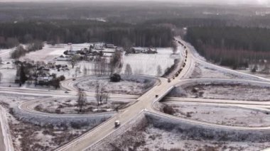 Valmiera, Letonya - 5 Ocak 2024 - Kırsal alanda karlı yollarda traktörlerle dolu bir kavşağın havadan görüntüsü. Çiftçi protesto konvoyu. 