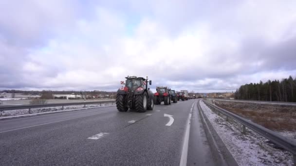 拉脱维亚瓦尔米拉 2024年2月5日 在多云的天空下 一辆由拖拉机和卡车组成的大篷车在雪地的路上 农民抗议政府的决定 — 图库视频影像
