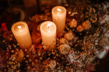 Valmiera, Letonya - 7 Temmuz 2023 - Çiçek aranjmanı arasında üç mum ve küçük çiçekler.