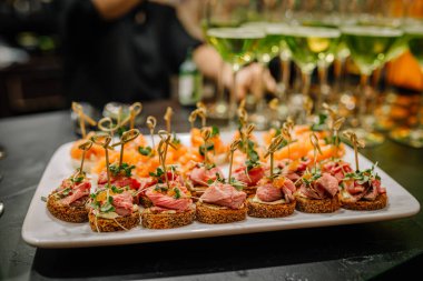 Riga, Latvia - January 18, 2024 - Canapes on a white plate with blurred background, catering at an event. clipart