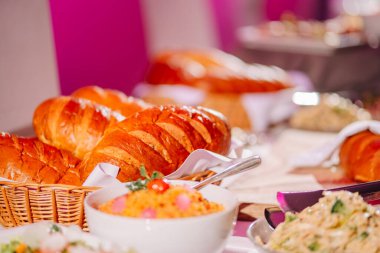 Sigulda, Letonya - 12 Ocak 2024 - Bir kruvasan, bir kase salata ve diğer yemeklerle dolu bir açık büfe.