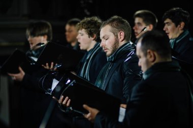 Valmiera, Letonya - 7 Ocak 2024 - Saint Simon Kilisesi. Siyah elbiseli ve elinde eşarpları olan erkek koro üyeleri, bir kilise konseri sırasında şarkı söylemeye odaklandılar..