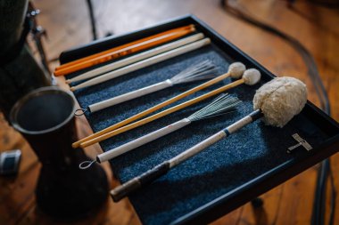 Valmiera, Letonya - 7 Ocak 2024 - Saint Simon Kilisesi. Bir davul ve metronomun yanında mavi astarlı siyah bir tepside duran çeşitli bagetler ve tokmaklar..