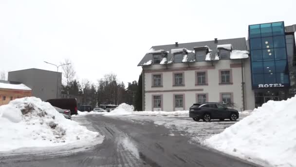 ラトビアのシグルダ 2024年2月13日 伝統的なセクション 雪の山の隣にモダンなガラスのファサードを備えたホテルビル — ストック動画