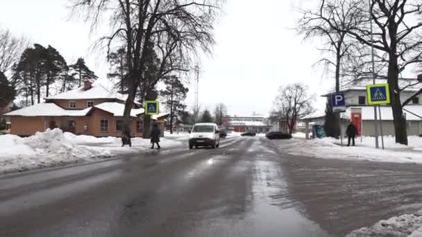 拉脱维亚Sigulda 2024年2月13日 在湿湿的街道上有人行横道标志 雪堆和一个人行走的车辆 — 图库视频影像