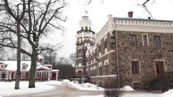 ラトビアのシグルダ 2024年2月13日 タワーのある石造りの建物 上に旗 地面に雪 赤木の家 裸の木 冬の日 — ストック動画