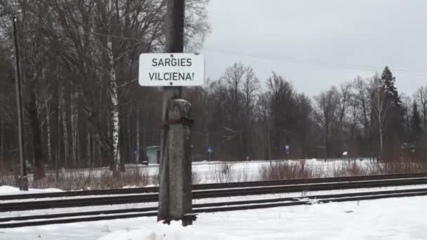 Sargies Vilciena 意思是 小心火车 拉脱维亚文 安装在一个木制柱子上 有积雪的背景和光秃秃的树木 — 图库视频影像