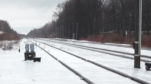 一个雪地的火车站站台 有多条铁轨延伸到远方 长椅和头顶布线 — 图库视频影像