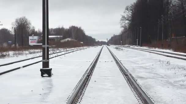 雨のために氷の層で覆われた鉄道トラック 背景に掲示板と裏側に並ぶ木々 — ストック動画