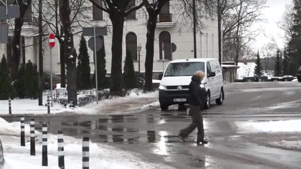 拉脱维亚塞西 2024年2月13日 一名行人穿过湿淋淋的街道 积雪融化 一辆白色面包车驶过 还有一些路标 其中包括一个禁止入内标志 — 图库视频影像