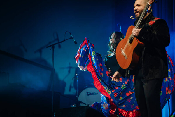 Valmiera, Latvia- February 15, 2024 - In the photo, a smiling male guitarist in embroidered clothing and a female dancer with a colorful dress are performing at a gypsy concert.