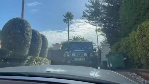 スペインのソトグランデ 2024年1月22日 景色とヤシの木に囲まれたゲートの外に駐車された視聴者に直面する別の車を示す車の内部からの眺め — ストック動画