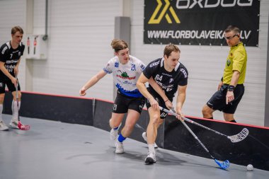 Valmiera, Letonya - 17 Şubat 2024 - biri siyahlı, biri beyazlı olmak üzere iki florbol oyuncusu, pist kenarında hakem gözlemcisi olarak yarışıyor..