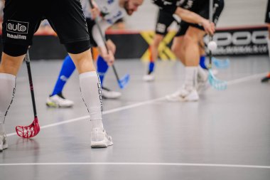 Valmiera, Letonya - 17 Şubat 2024 - Bir oyun sırasında oyuncuların bacakları ve florbol sopaları yakın çekim, hareket ve ekipman odaklı.