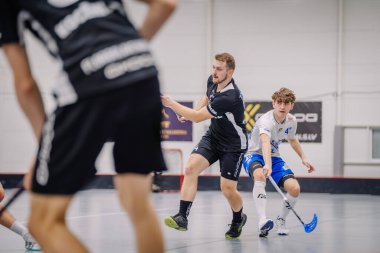 Valmiera, Letonya - 17 Şubat 2024 - iki florbol oyuncusu hareket halinde, biri siyahlı, biri beyazlı, yarışmaya odaklı.