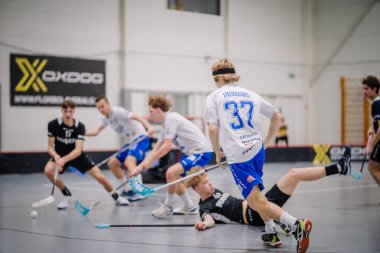 Valmiera, Letonya - 17 Şubat 2024 - Beyazlı bir oyuncunun topa vurmak üzere olduğu dinamik bir florbol oyunu.