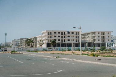 Agadir, Fas - 25 Şubat 2024 - seyrek bitki örtüsü ve açık gökyüzü olan gelişmekte olan bir alanda yeni apartmanlar inşa ediliyor.