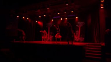 Agadir, Fas - 25 Şubat 2024 - Sahnede kabile kostümlü dansçılar ağaç zemin ve mor ışıkla gösteri yapıyorlar.