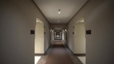 Agadir, Fas - 25 Şubat 2024 - Bir otel koridoru oda kapıları, çıkış işaretleri, tavan ışıkları ve desenli bir zemin.