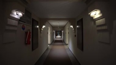 Agadir, Fas - 25 Şubat 2024 - Bir otel koridoru oda kapıları, çıkış işaretleri, tavan ışıkları ve desenli bir zemin.
